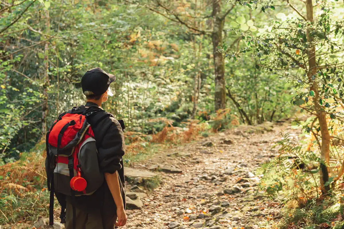 Une femme avec un sac à dos qui marche en pleine forêt