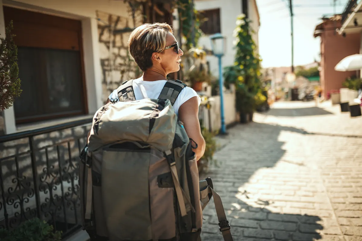 Une femme qui marche dans la rue avec un sac à dos de voyage