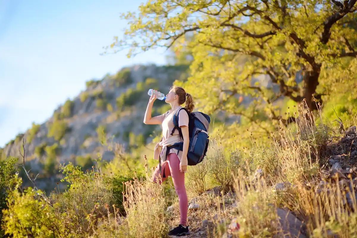 Une femme qui boit de l'eau en pleine nature