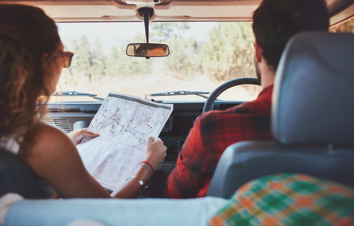Un couple dans une voiture. La femme tient un plan à côté du conducteur
