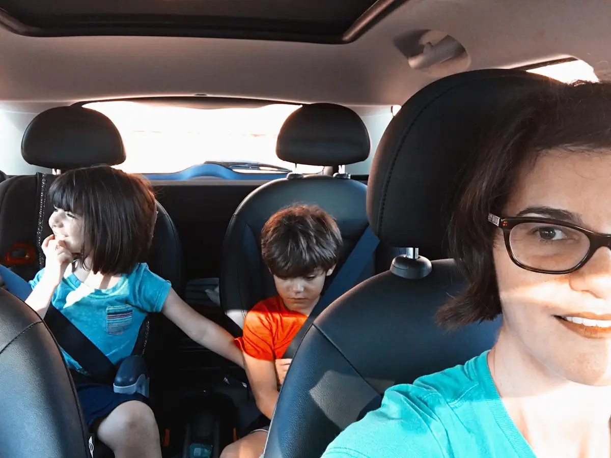 Des enfants à l'arrière d'une voiture avec une femme sur le devant